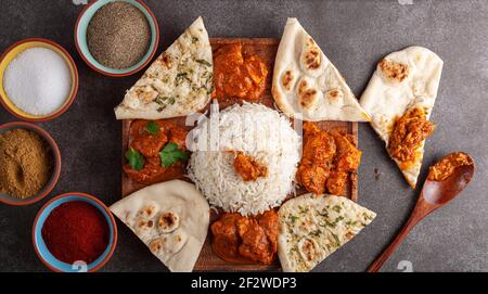 Flaches Lay-Bild von einer Platte mit traditionellen indischen Speisen. Curried Chicken, Tikka Masala, Paneer, Butter Chicken und pav bhaji in Portionen dazwischen gesehen Stockfoto