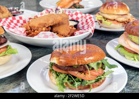 Voller Tisch mit einer Vielzahl von Restaurant-Gerichte zur Auswahl mit veganen Burger in der Mitte. Stockfoto