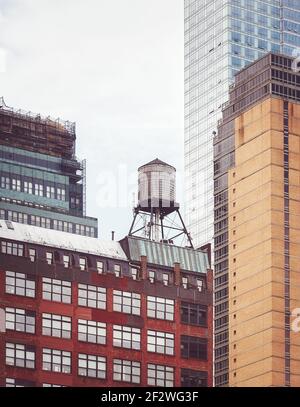 Alter Wasserturm, eines der New York City Symbole, unter modernen Gebäuden, Farbtonierung angewendet, USA. Stockfoto