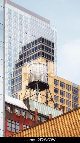 Alter Wasserturm zwischen modernen Gebäuden, New York City, USA. Stockfoto