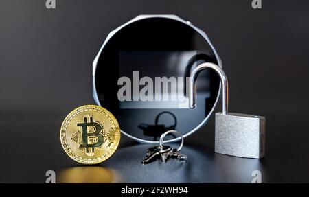 Ein Bitcoin und ein Schloss vor einem Cryptocurrency Hardware Wallet. Stockfoto