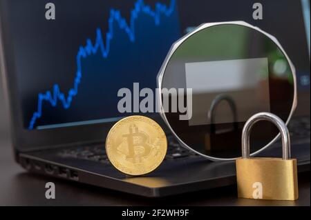 Eine digitale Brieftasche, ein Bitcoin und ein Schloss auf einem Notebook. Stockfoto