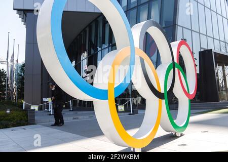 Tokio, Japan. März 2021, 11th. Ein Mann mit Gesichtsmaske steht hinter den olympischen Symbolen der fünf verschachtelten Ringe, die in der Nähe des Nationalstadions in Tokio abgebildet sind. Etwa 80% der Japaner in den letzten Umfragen sagen, dass die Olympischen Spiele verschoben oder abgesagt werden sollten, und fast so viele wollen keine Fans aus dem Ausland. (Foto von James Matsumoto/SOPA Images/Sipa USA) Quelle: SIPA USA/Alamy Live News Stockfoto