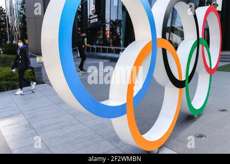 Tokio, Japan. März 2021, 11th. Ein Mann mit Gesichtsmast geht hinter die olympischen Symbole der fünf verschränkte Ringe in der Nähe des Nationalstadions in Tokio. Etwa 80% der Japaner in den letzten Umfragen sagen, dass die Olympischen Spiele verschoben oder abgesagt werden sollten, und fast so viele wollen keine Fans aus dem Ausland. Kredit: SOPA Images Limited/Alamy Live Nachrichten Stockfoto