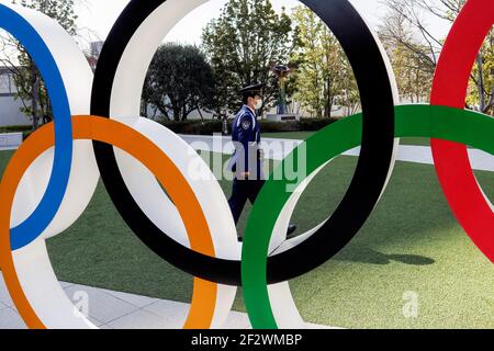 Tokio, Japan. März 2021, 11th. Ein Mann mit Gesichtsmast geht hinter die olympischen Symbole der fünf verschränkte Ringe in der Nähe des Nationalstadions in Tokio. Etwa 80% der Japaner in den letzten Umfragen sagen, dass die Olympischen Spiele verschoben oder abgesagt werden sollten, und fast so viele wollen keine Fans aus dem Ausland. Kredit: SOPA Images Limited/Alamy Live Nachrichten Stockfoto