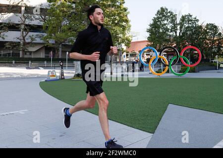 Tokio, Japan. März 2021, 11th. Ein Mann joggt an den olympischen Symbolen der fünf verschachtelten Ringe vorbei, die in der Nähe des Nationalstadions in Tokio abgebildet sind. Etwa 80% der Japaner in den letzten Umfragen sagen, dass die Olympischen Spiele verschoben oder abgesagt werden sollten, und fast so viele wollen keine Fans aus dem Ausland. Kredit: SOPA Images Limited/Alamy Live Nachrichten Stockfoto