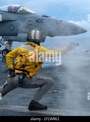 US Navy LT. Colin Zimmermann signalisiert, ein FA-18E Super Hornet Kampfflugzeug, das den Golden Warriors of Strike Fighter Squadron 87 zugewiesen wurde, vom Flugdeck an Bord des Nimitz-Klasse Flugzeugträgers USS Theodore Roosevelt am 12. März 2021 im Indischen Ozean zu starten. Stockfoto