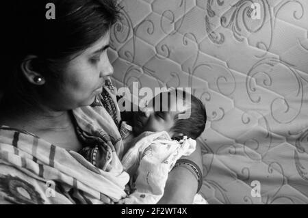 Nahaufnahme Gesicht eines niedlichen neugeborenen Jungen schaut glücklich auf seine Mutter in ihrer Mutter Schoß. Ein Monat altes süßes kleines Kleinkind Kleinkind. Indische Ethnie. F Stockfoto