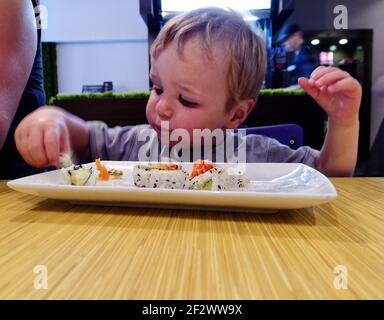 Ein kleiner Junge (2 Jahre) Sushi essen in einem Restaurant Stockfoto