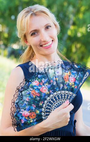 Schönes Porträt einer jungen Frau mit einem Fächer in der Natur. Stockfoto