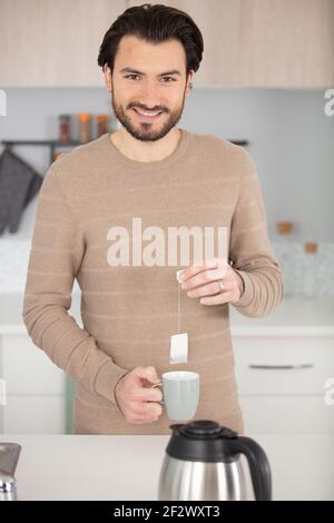 Mann hält Teebeutel über einer Tasse Stockfoto