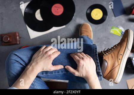 Herren Hand am Bein in Jeans mit alten Reisen Lederstiefel Schuhe. Entspannung und Kunst Musik Lifestyle Konzept Stockfoto