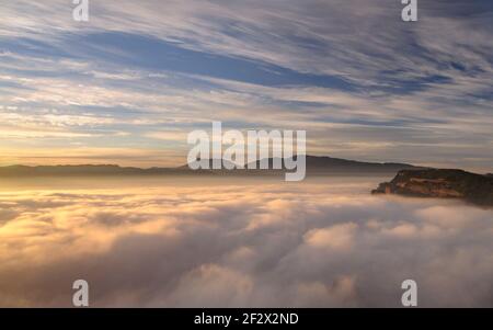 Sonnenaufgang mit einem Meer von Wolken über dem Dorf Vilanova de Sau. Blick vom Gipfel Roca del Migdia (Osona, Katalonien, Spanien) Stockfoto