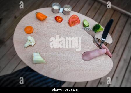 Künstler Holzpalette, auf der Gemüse platziert werden. In den Tassen gibt es Gemüse Dip. Ein Messer, eine Gabel und die Hand eines Männchens. Stockfoto