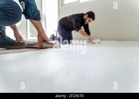 Zwei Männer installieren eine isolierende Schicht auf dem Boden von Das Haus Stockfoto
