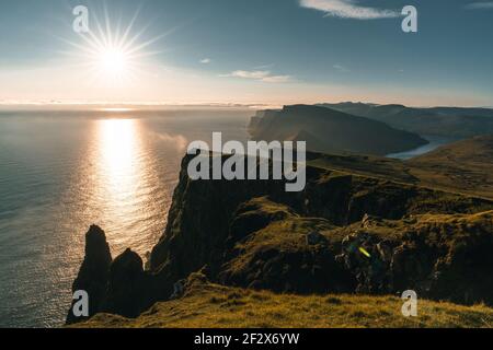 Luftdrohnenpanorama auf den Färöer Inseln Sud in Richtung Beinisvord bei Sonnenuntergang. Stockfoto