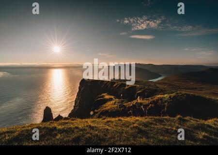 Luftdrohnenpanorama auf den Färöer Inseln Sud in Richtung Beinisvord bei Sonnenuntergang. Stockfoto