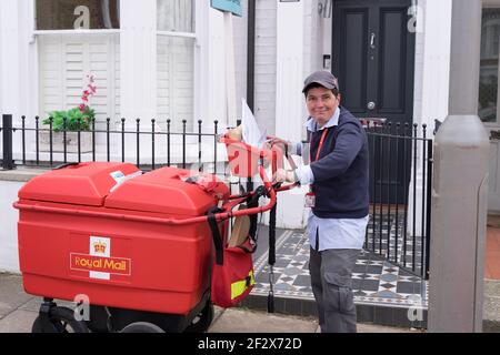 royal Mail Postal Lady lächelt neben ihrem Postwagen stehen, Trolley liefert Post und Pakete an die Bewohner in clapham Common, Süd-london, Großbritannien Stockfoto