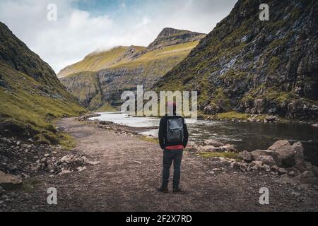 Junger Tourist, der im saksun-Tal auf einem Wanderweg auf den färöer-Inseln auf der Hauptinsel Streymoy steht. Stockfoto