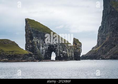 Nahaufnahme der berühmten Drangarnitr Klippe mit den Tindholmur Inseln in Der Hintergrund wurde während der morgendlichen Wanderung im Frühjahr aufgenommen Färöische Küste Stockfoto