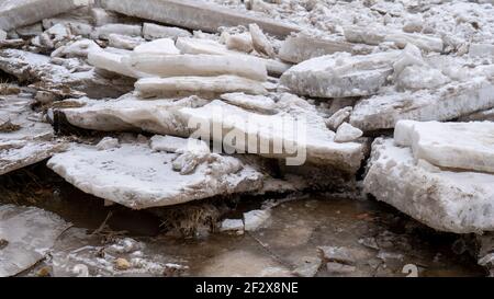 Riesige Eisladungen treiben im Fluss Ogre, Lettland. Staus auf dem Fluss im Frühling. Ein großer Haufen bewegter Eisblöcke Stockfoto