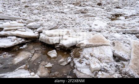 Riesige Eisladungen treiben im Fluss Ogre, Lettland. Staus auf dem Fluss im Frühling. Ein großer Haufen bewegter Eisblöcke Stockfoto