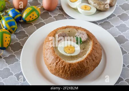 Die saure Suppe (zurek) aus Roggenmehl mit Wurst und Ei in Brotschale serviert. Beliebtes Ostergericht. Stockfoto