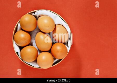 Ungekochte Eier in runder Schachtel auf orangefarbenem Hintergrund Stockfoto