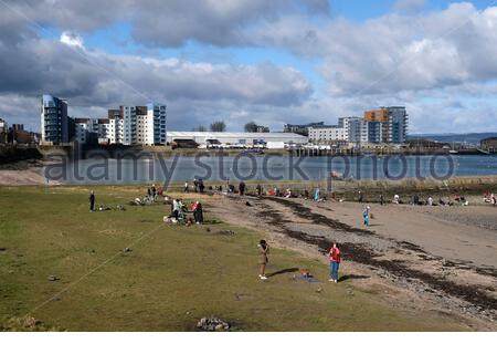 Menschen genießen Granton Hafen Wellenbrecher und Wardie Bay an einem sonnigen Tag, Edinburgh, Schottland Stockfoto