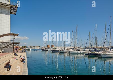 Kajakfahrer aus dem echten Club nautico segeln in ihren roten Kanus durch die Gewässer des Grao de Castellon, mit den Yachten im Hintergrund, Spanien Stockfoto