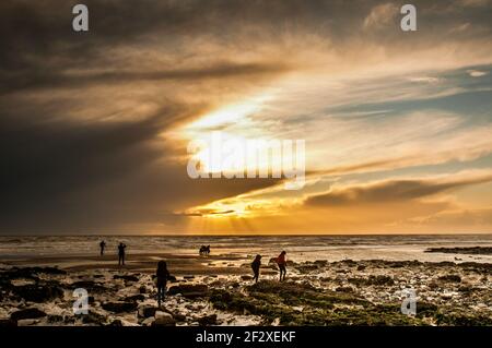 Birling Gap, Eastbourne, East Sussex, Großbritannien. März 2021, 13th. Ein wirklich zauberhafter Abschluss des Tages nach Gewitter Regen und Hagel Stürmen. Der belebende Südwestwind hielt Hundewanderer, Rockpooler, Fotografen und Familien nicht davon ab, die Aussicht zu genießen und die frische Luft zu genießen, da der Sonnenuntergang ein orangefarbenes Leuchten und Meeresnebel einwirft. Kredit: David Burr/Alamy Live Nachrichten Stockfoto