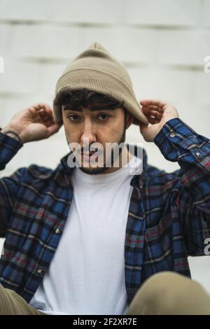 Ein Porträt eines coolen spanischen Mannes, der lässig angezogen ist Unscharfer Wandhintergrund Stockfoto