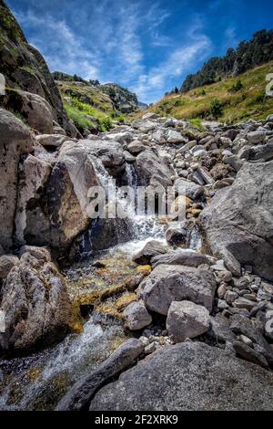 Schmelzwasserfluss fließt durch eine felsige Schlucht von der Spitze eines Berges, im Naturpark von Aiguestortes, in den katalanischen Pyrenäen von Lerida, Spanien Stockfoto