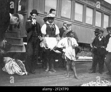 Billy Bowlegs III, alias Billy Fewell oder Cofehapkee (1862–1965), Seminole Elder (ebenfalls afroamerikanischer Abstammung) und Stammeshistoriker, stehen mit anderen Männern neben einem Zug in Ft. Pierce, Florida, 1896. Bogenschenkel war der Enkel von Osceola und war Mitglied des Schlangenclans. Stockfoto