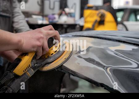 Crop anonymen männlichen Mechaniker mit Maschine zum Polieren Auto, während Vorbereitung Automobil für Malerei in der Werkstatt Stockfoto