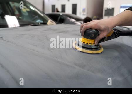 Crop anonymen männlichen Mechaniker mit Maschine zum Polieren Auto, während Vorbereitung Automobil für Malerei in der Werkstatt Stockfoto