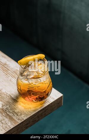 Von oben Tiki Glas Tasse mit Alkohol auf gelegt Rand des Holztisches im Raum auf unscharfem Hintergrund Stockfoto