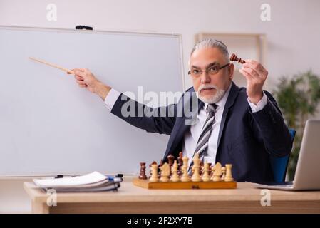 Alter Geschäftsmann Angestellter, der Schach am Arbeitsplatz spielt Stockfoto