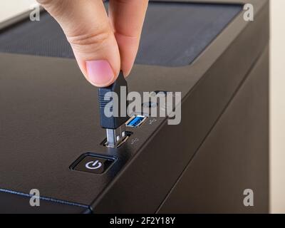 Personenfinger stecken das USB-Kabel in den oberen Anschluss des Computerturmgehäuses. Informationstransfer und -Speichergerät. USB-Steckverbinder standardmäßig. Stockfoto