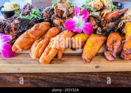 Teller mit tropischen Lebensmitteln Jerk Chicken BBQ Ribs Gebratene Kochbananen Auf einer Platte Stockfoto