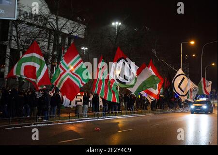 Warschau, Warschau, Polen. März 2021, 13th. Warschau Legia Fußballmannschaftsfans winken Flaggen vor dem Legia-Stadion, das wegen der Sperre während eines Spiels am 13. März 2021 in Warschau, Polen, für die Öffentlichkeit geschlossen wurde. Rund tausend Fans der Warschauer Legia-Fußballmannschaft nahmen an einer regierungsfeindlichen Demonstration gegen die Beschränkungen des Covid-19 unter dem Motto "Offene Stadien" Teil und forderten mindestens 50 Prozent der verfügbaren Plätze während der Spiele. Quelle: Aleksander Kalka/ZUMA Wire/Alamy Live News Stockfoto