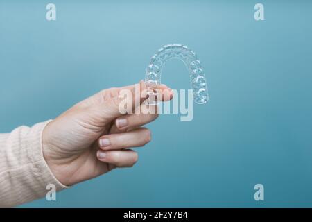 Frauenhand hält einen seitlich beleuchteten transparenten Halter auf blau Hintergrund Stockfoto