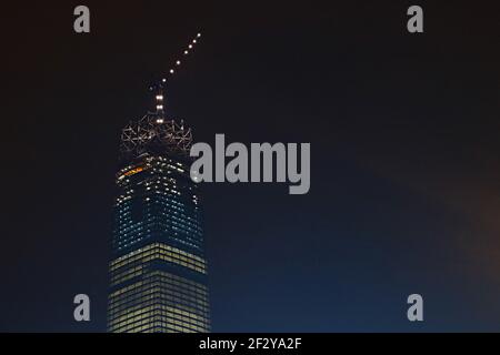 Die Börse 106' im Bau Nachts ein fast fertiggestellte Wolkenkratzer mit einem Kran oben und nur noch die Glaskrone zum Bau: Stockfoto