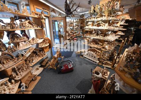 Oberammergau, Deutschland. Februar 2021, 17th. Eine geschlossene Holzschnitzerei ist reich gefüllt mit Krippen, heiligen Figuren und Kruzifixen, dazwischen ein Staubsauger. Das Geschäft mit Weihnachtskrippen, aber vor allem mit Kruzifixen, läuft das ganze Jahr über - aber die wichtige Vorweihnachtszeit und vor allem die Passion werden 2020 wegen der Pandemie abgesagt. Quelle: Angelika Warmuth/dpa/Alamy Live News Stockfoto