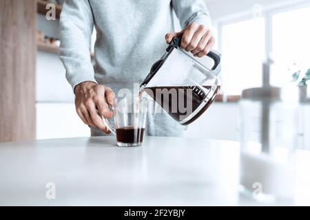 Der Mensch schenkt sich eine Tasse Kaffee Stockfoto