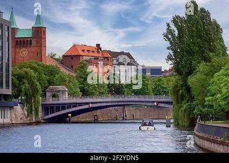 Kleines Boot schwimmt auf Flusswasser unter Brücke in der Nähe der historischen St. Nikolaus Kirche entlang der Spree Kanal Stockfoto