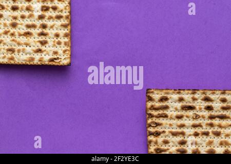 Eine Nahaufnahme von zwei Matzahs - Brot für das jüdische Passah, auf einem violetten Hintergrund Stockfoto