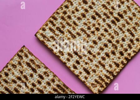 Eine Nahaufnahme von zwei Matzahs - Brot für das jüdische Passah, auf einem rosa Hintergrund Stockfoto