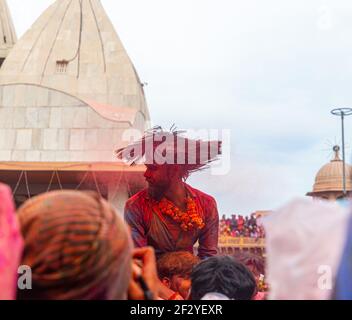 Ein Mann schüttelt den Kopf, indem er Gulal in die Haare setzt, mit selektivem Fokus auf das Motiv mit zusätzlichem Rauschen und Körnern. Stockfoto