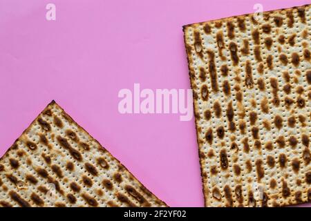 Eine Nahaufnahme von zwei Matzahs - Brot für das jüdische Passah, auf einem rosa Hintergrund Stockfoto